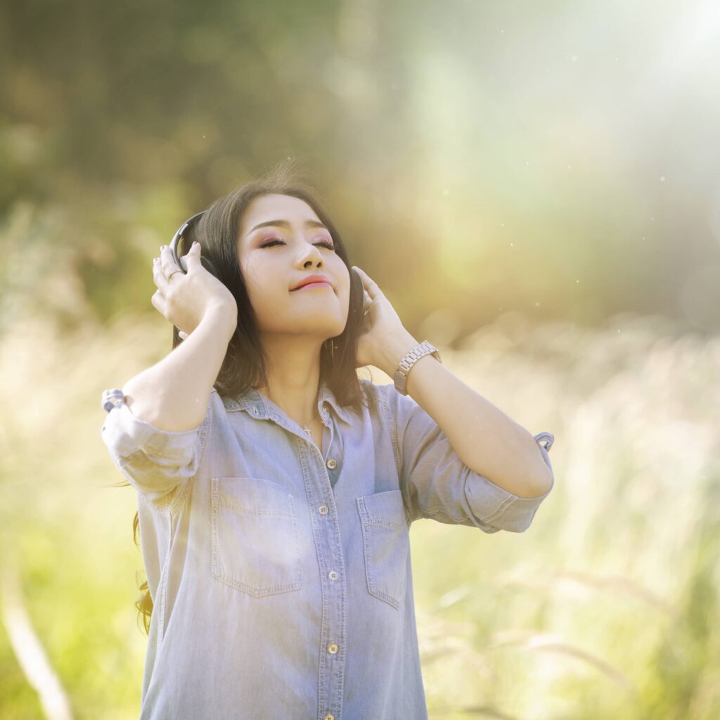 woman relax by listening music with headphone in the nature green park girl happy 1