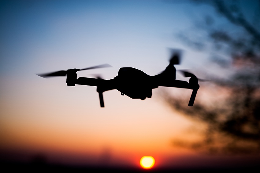 flying drone into the sunset silhouette against sun quad copter in motion