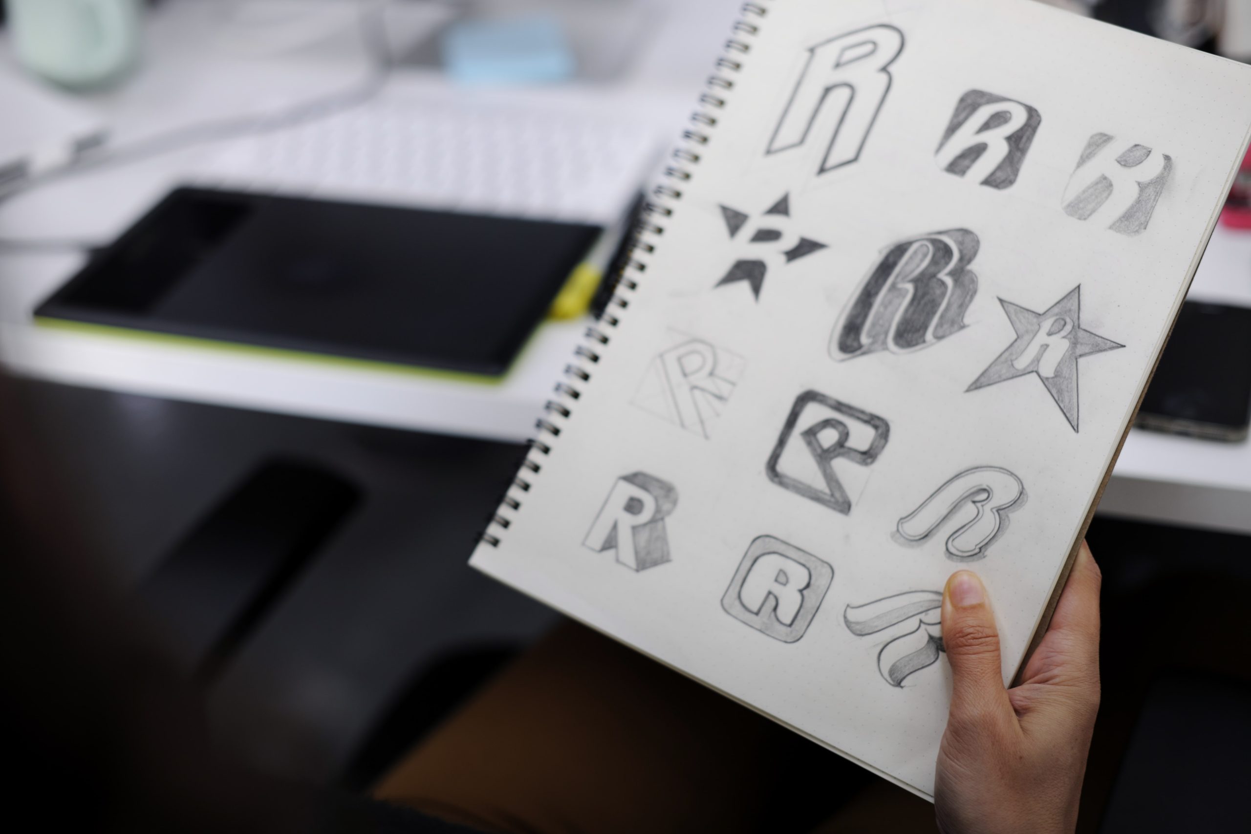 hand holding notebook with drew brand logo creative design ideas min scaled